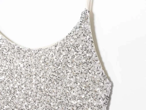 Detail of silver sequin dress showing V-neck design and thin spaghetti straps texture