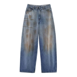 Détail du jean taille haute à jambe large avec délavage vintage et bouton croisé à la taille