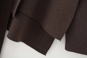 Detail of coffee brown knit poncho texture and layered asymmetric hem stitching