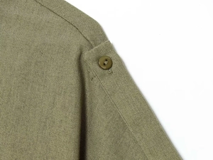 Detailed view of olive green shoulder strap with button on twill fabric jacket