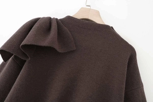 Detailed view of the dark brown knit sweater featuring oversized ruffle trim on shoulder