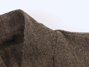 Detailed close-up of brown herringbone fabric and collar stitching on a casual blazer