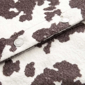 Macro detail of plush animal print jacket fabric with embossed silver metal button