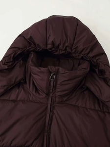 Detail of high neck windproof zipper and quilted hood on a burgundy winter puffer coat