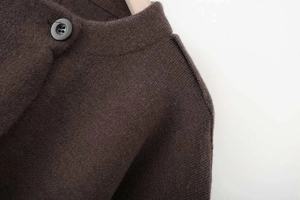 Detailed macro view of dark brown knit cardigan with round neck and single black button