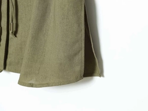 Detailed view of olive green fabric with drawstring, metallic tip and side slit hem