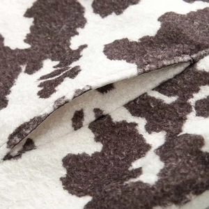 Close-up of animal print jacket fabric showing black and white cow patterns and pocket