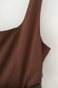 Detail of a brown A-line dress featuring wide straps, square neck, and a black belt with buckle