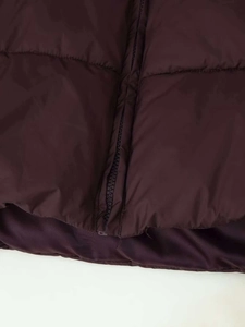 Detail of burgundy puffer coat featuring horizontal quilting and matching zipper closure