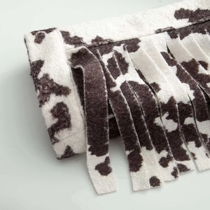 Close-up of black and white cow print jacket featuring soft faux fur texture and fringe