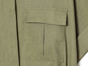 Detail of olive green shirt featuring utility chest pocket and woven cotton linen texture