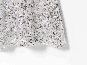 Close-up of shimmering silver sequins on a stylish summer slip dress with metallic finish