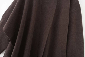 Detail shot showing the soft texture and fine knit of the dark coffee asymmetrical poncho