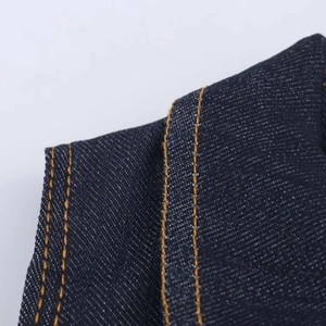 Dettaglio della tuta in denim a vita alta con doppie cuciture a contrasto