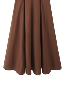 Detail view of caramel brown A-line dress hem with smooth pleats and structured fabric
