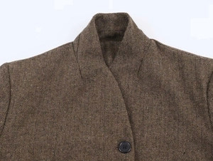 Macro detail of brown herringbone wool jacket showing stand collar and dark resin button