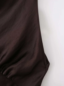 Detail of deep brown satin mini dress showing silk texture and ruffled hemline stitching