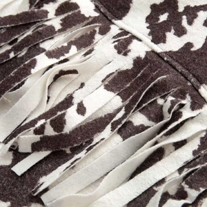 Macro shot of faux cowhide animal print fabric with western-style fringe trim detailing