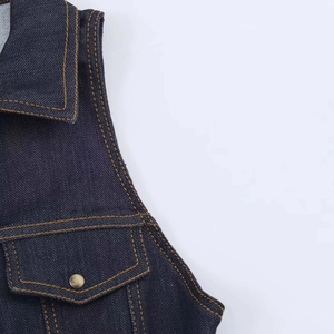 Dettaglio in denim blu scuro con cuciture a contrasto e bottone in metallo sulla tasca
