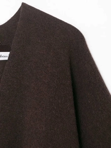Detail of dark brown knit poncho fabric texture and MWOMAN brand label on the neckline