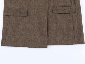 Close-up of brown herringbone tweed fabric texture with flap pocket on blazer