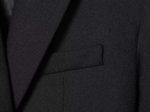 Detail of black cropped blazer featuring notch lapels and a chest pocket with matte texture