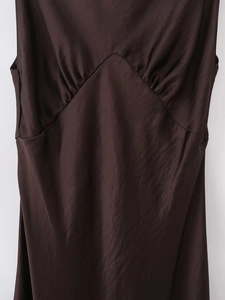 Detailed macro view of chocolate satin fabric texture and V-shaped seam with soft pleats
