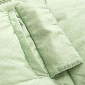 Détail de la veste matelassée vert clair avec motifs cœurs et coutures de poche