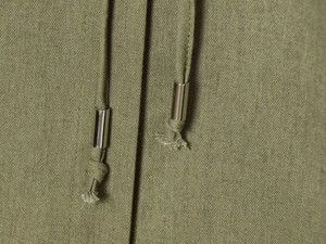 Detail of olive green fabric with drawstring and polished silver metal aglets