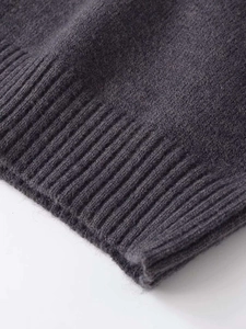 Detailed macro view of charcoal grey knit sweater showing fine texture and ribbed edge