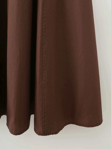 Close-up of caramel brown dress hem showing high-quality stitching and fabric texture