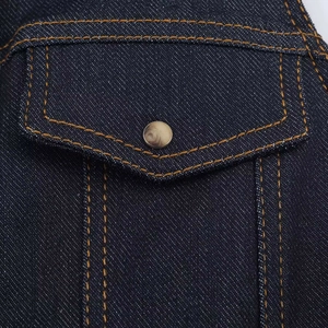 Dettaglio di denim blu scuro con cuciture gialle a contrasto e bottone a pressione