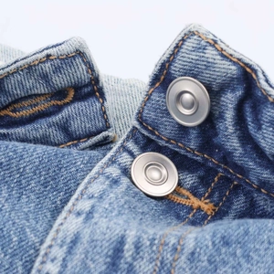 Détail du jean taille haute montrant les doubles boutons en métal et les surpiqûres orange