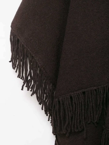 Close-up of dark brown knit cape with fine wool texture and long decorative fringes
