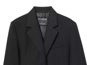 Detailed close-up of notch lapel and brand size label on black cropped blazer jacket