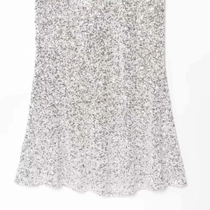 Close-up of sparkling silver sequin dress with elegant scalloped hem and high density glitter