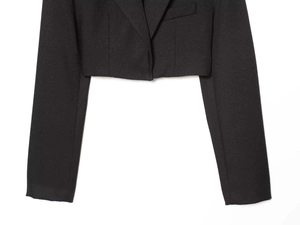 Detail of a black cropped blazer featuring textured fabric and sharp suit collar tailoring