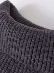 Detail of dark grey rib-knit turtleneck sweater showing high-quality wool-like texture