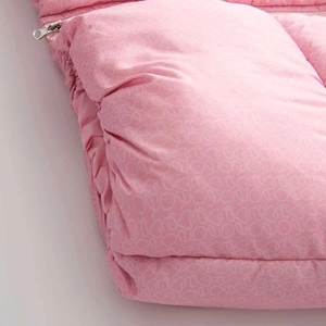Détail du tissu matelassé rose avec motifs de cœur et tirette de fermeture éclair