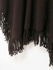 Detail view of deep brown knitted poncho featuring soft texture and thick tassel fringe trim