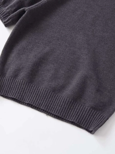 Detailed macro view of the ribbed hem and soft knit texture of a dark grey knit top