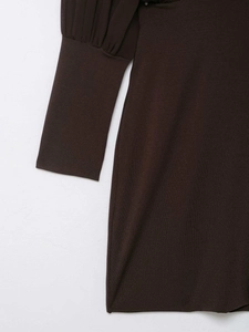 Dettaglio della trama in maglia marrone scuro ed eleganti pieghe sui polsini delle maniche