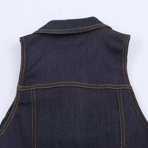 Dettaglio di una tuta in denim blu scuro con doppie cuciture gialle a contrasto