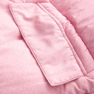 Gros plan du tissu matelassé rose de la veste avec motif logo et couture de poche