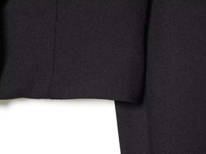 Detailed macro view of black twill fabric texture and precise stitching on the suit jacket