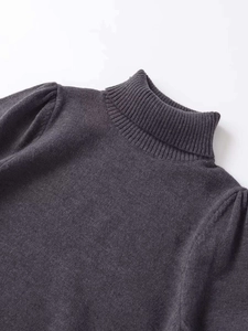 Close-up detail of dark grey high-neck knitwear featuring ribbed collar and puffed sleeves