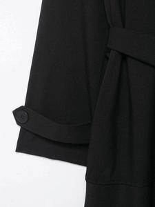 Detailansicht der Ärmelschlaufe und der dichten Stoffstruktur des schwarzen Trenchcoats
