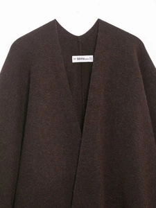 Close-up of brand label and textured wool fabric on a brown knit tassel poncho