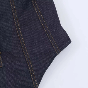 Dettaglio delle cuciture su denim blu scuro con doppie linee di cucitura arancioni