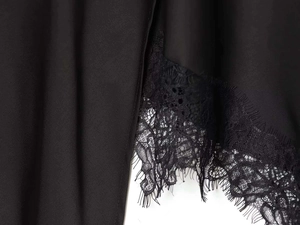 Détail de l'ourlet de la jupe noire avec dentelle de cils délicate et broderies florales